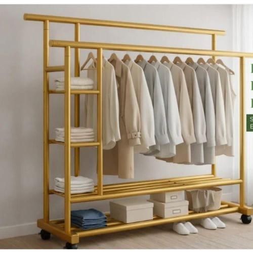 gold-colored, heavy-duty mobile clothes rack featuring double hanging rails, integrated side shelving, and rolling wheels.