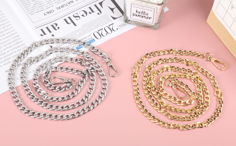 Two metal chain necklaces or bracelets, one silver-toned and one gold-toned, displayed on a pink surface with partially visible text and objects.