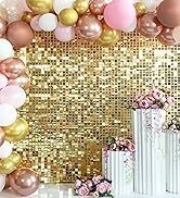 Party decoration setup with gold sequin backdrop, balloon arch in pink, gold, and white, and white floral-filled vases. Elegant event backdrop for photos or celebrations.