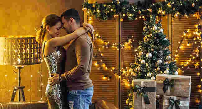 a couple embraces in front of a christmas tree