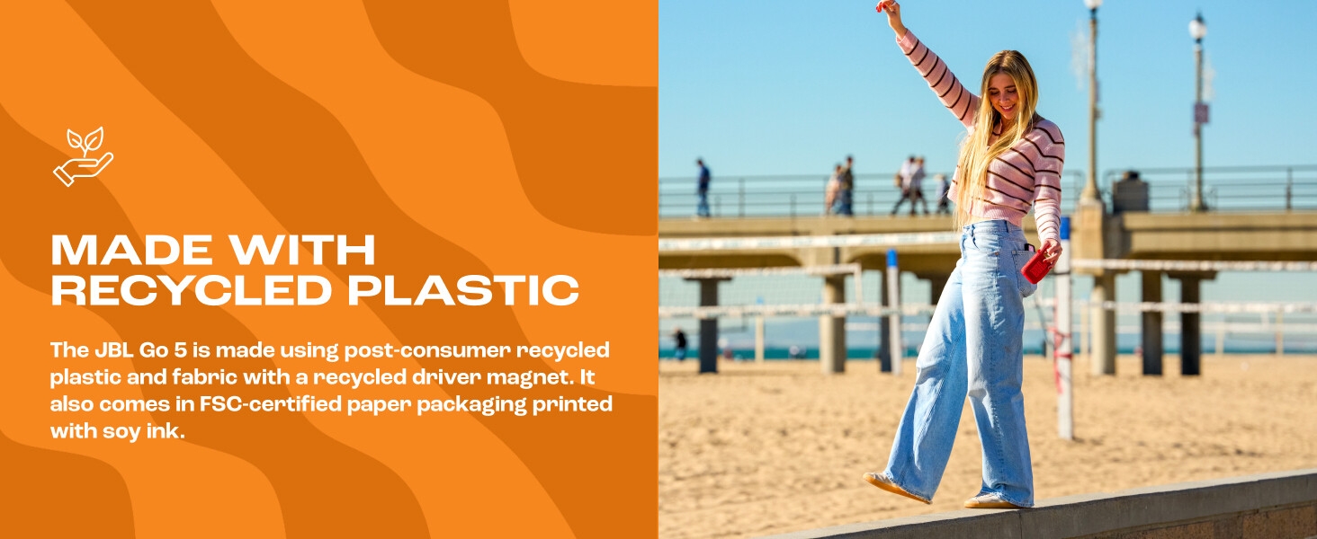 Text reads 'MADE WITH RECYCLED PLASTIC' and sustainability description. Woman in colorful top standing on pier with raised arm, ocean and buildings visible in background.