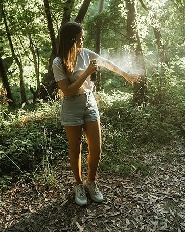 woman sprays natural bug spray on her body to repel mosquitoes for 6 hours