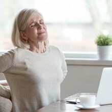 Woman in pain at her desk with a laptop.